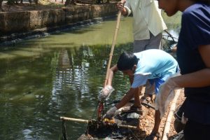 A kid from the slum area helps in cleaning the creek